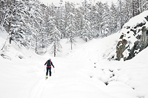 Backcountry skier walks in a snowy mountain valley
